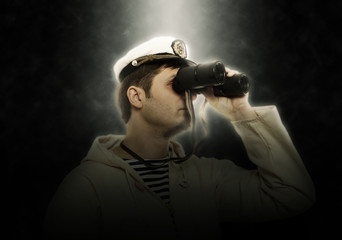 Man in captain hat looks on binocular