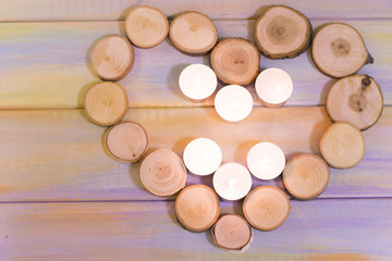 Obraz na płótnie Canvas The concept of St. Valentine's Day, Love, Wedding, Anniversary with six burning aroma candles in a heart shaped frame of tree circles, colored wooden background, top view