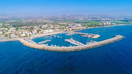 Fotobehang Luchtfoto vanuit vogelperspectief van de haven van het vissersdorp Zygi, Larnaca, Cyprus. De vissersboten legden aan in de haven met aangemeerde jachten en de skyline van de stad bij Limassol van bovenaf. © f8grapher