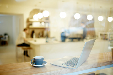 Empty workplace of modern manager in cafe with cup of tea and laptop