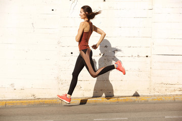 Full body healthy young woman sprinting outdoors in the city