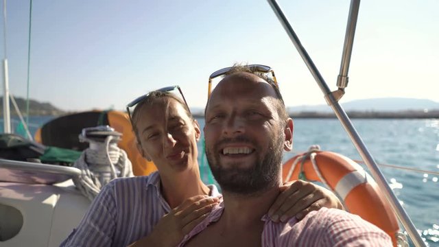 Happy couple taking selfie photos while sailing boat on ocean
