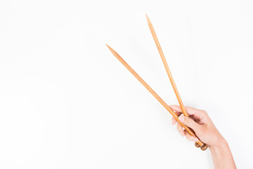 Woman hand with two wooden knitting needles over white background