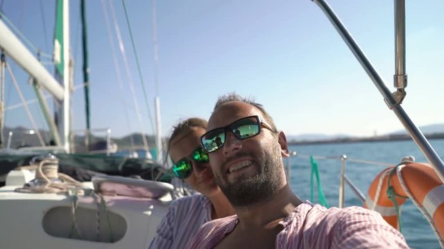 Happy couple taking selfie photos while sailing boat on ocean
