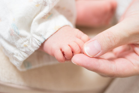 赤ちゃんの足に触れる母親の手