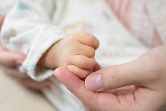 赤ちゃんの手に触れる母親の手