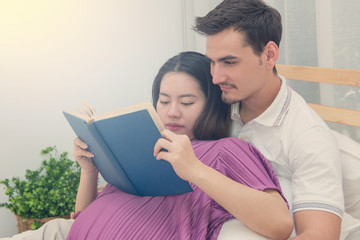 Fototapeta premium pregnant woman and her handsome husband reading a book