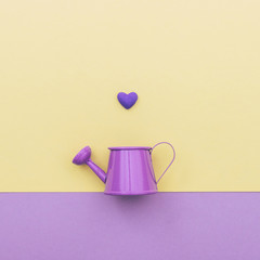 purple watering can for flowers and one heart on top of dual-colored background
