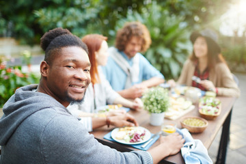 Young African man looking at camera by festive table outdoors