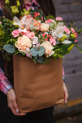 female hands holding a paper box with flowers