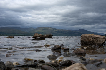 Fototapeta na wymiar Rocks leading out into the fresh water of Loch Lomond Scotland