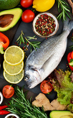 Food background. Fresh, raw Dorado with a swallow, lemon, avocado on a dark concrete background.