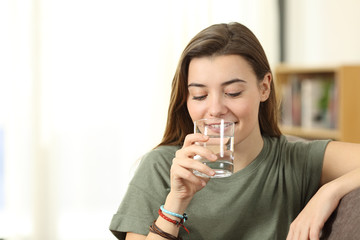 Teen drinking water from a glass at home