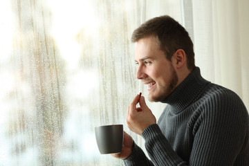 Happy man taking a pill in winter at home