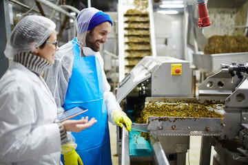 Two workers of seafood plant having talk by producing-line of seaweed salad © pressmaster