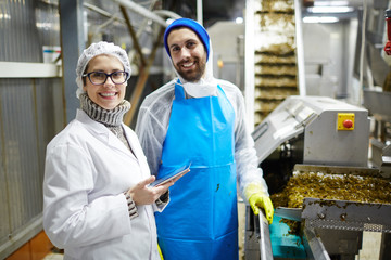 Succesful workers of seafood producing factory in uniform looking at camera at work