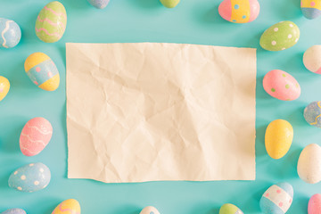 Coloeful easter eggs and brown paper on pastel color background with space.