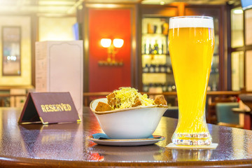 A glass of unfiltered beer with rusks cheese, a tablet - is reserved on a wooden table in the restaurant bar.
