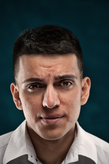 Fototapeta premium Close-up portrait of young handsome man showing frustrated emotions on dark blue background