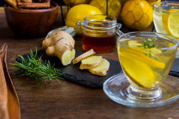 Glass cup of hot tea with mint, honey, ginger and lemon on dark background.