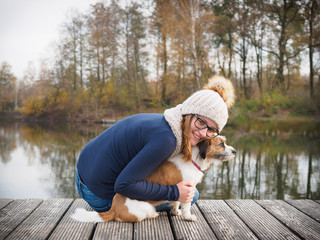Junges Mädchen mit Hund auf einem Holzsteg am See. Reale Menschen, beste Freunde, Lebensfreude,...