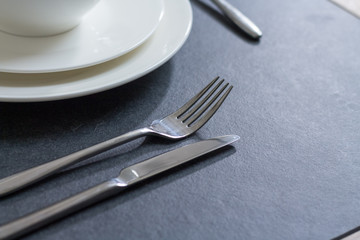 Table setting dinner plate with cutlery on dark background