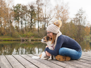 Fototapeta premium Junges Mädchen mit Hund auf einem Holzsteg am See. Lebensfreude, beste Freunde, Glück, Natur.