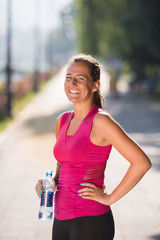 woman drinking water from a bottle after jogging