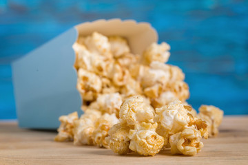 Popcorn in blue cardboard package on table against blue background
