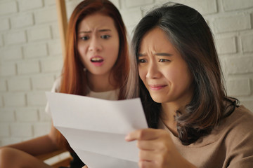 frustrated, shocked women looking at expensive bill or debt notice invoice