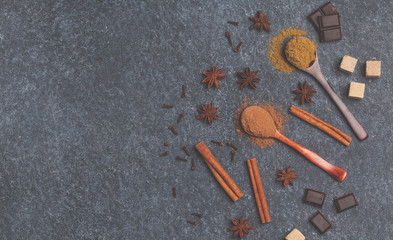 Selection of sugar, chocolate, spices, cocoa powder. Ingredients for cooking cocoa. Dark background, top view, copy space. Winter beverage concept.