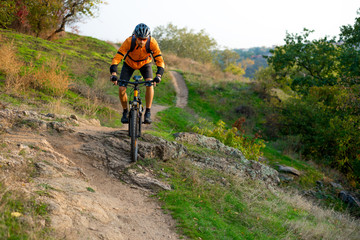 Fototapeta na wymiar Cyclist in Orange Riding the Mountain Bike on the Autumn Rocky Trail. Extreme Sport and Enduro Biking Concept.