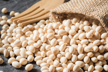 Many white beans on table with burlap bag