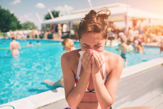 picture from a Beautiful women in bikini with handkerchief. Sick female model has runny nose. girl makes a cure for the common cold. She is sick in the summer on vacation.