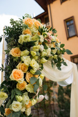 Closeup of beautiful wedding arch with fresh flowers in beige colors in the garden