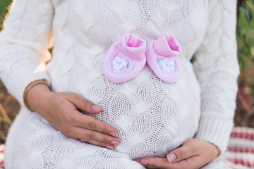 Belly of a pregnant woman with newborn pink baby booties