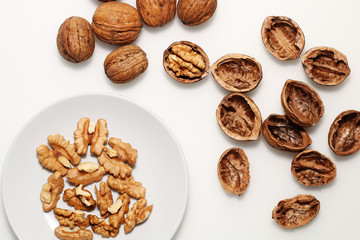 Open and closed walnuts on a white plate and a white background