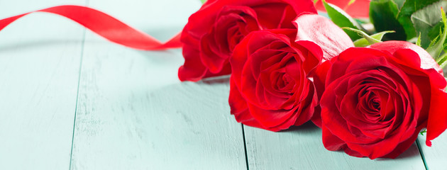 Fresh red roses on aquamarine table