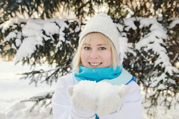 Fototapeta na wymiar beautiful blond smiling girl holding snow on the palms