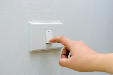 Save electricity Close up of finger is turning on or off on light switch. womans hand with finger on light switch Copy space.