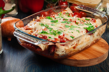 Traditional mexican enchiladas with chicken meat, spicy tomato sauce and cheese in heat resistant dish