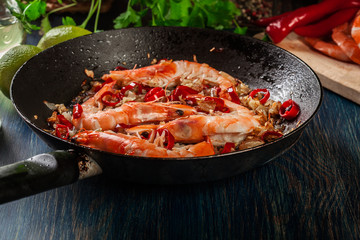 Shrimps roasted on frying pan with onion, garlic and chili