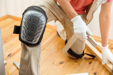 worker in the knee pads marks the wooden boards