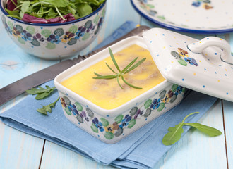 Chicken liver pate with butter and thyme in ceramic form and green salad, selective focus
