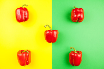 Top view on five fresh sweet red peppers on two colored background in yellow and green