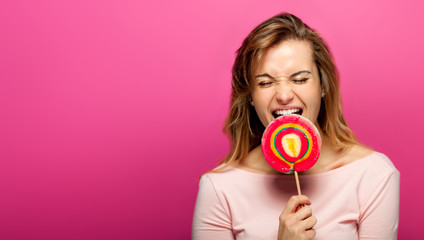 Beautiful young woman with big lollipop on pink background, copy space