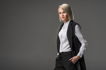 Obraz premium side view of stylish young woman in white shirt posing isolated on grey