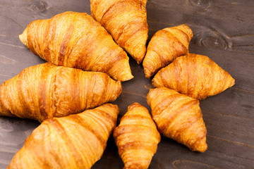 Mini and maxi croissants lying on wooden table. Close up