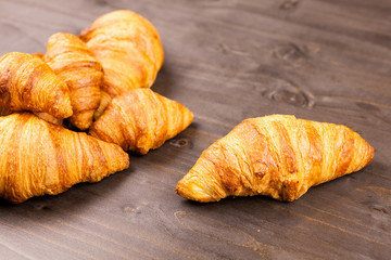 Fresly baked golden croissants lying on a wooden table