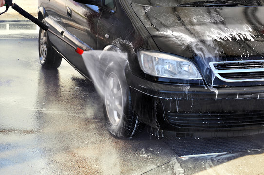 Cleaning Car Using High Pressure Water. Man washing his car under high pressure water in service 
